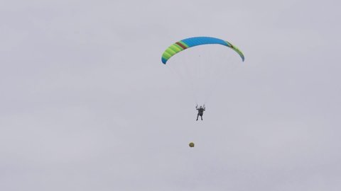 Bottom view of man with parachute in sky. Action. Person flies in sky on paraglider in cloudy weather. Extreme sports and skydiving