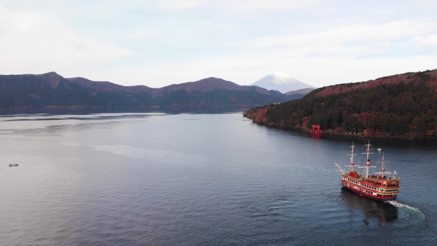 Flying over a pirate ship on Lake Ashi near the historic Hakone Torii Gate with Mount Fuji in the background Royalty-Free Stock Footage #1062999190