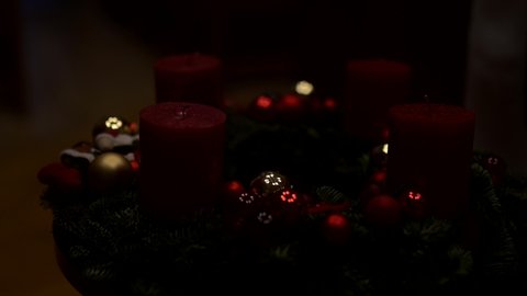 A close-up of Christmas decorations in the Advent wreath. First Advent in December. Flickering candle with warm light and Christmas baubles. Religious tradition in the Christmas season.