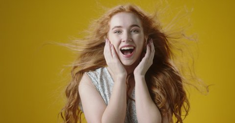 Expressive authentic beautiful redhead caucasian girl looking at camera and getting shocked. Amazed young woman screaming from happiness 4k footage