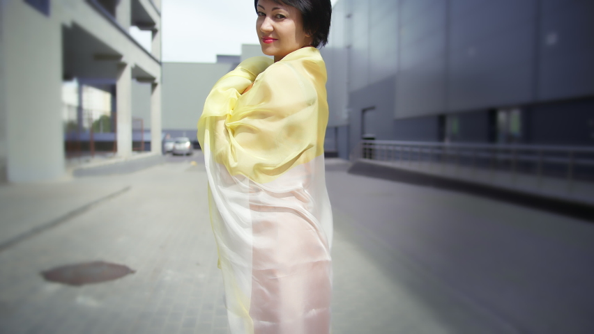 woman playing with a scarf on the street and looking at the camera, stylish woman outdoors