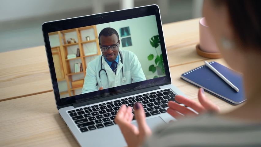 Telemedicine conference on laptop. Patient talk to African doctor from home. Spbas View over shoulder, coronavirus sick person consulting with physician. Concept of telehealth, video call, computer | Shutterstock HD Video #1063013542