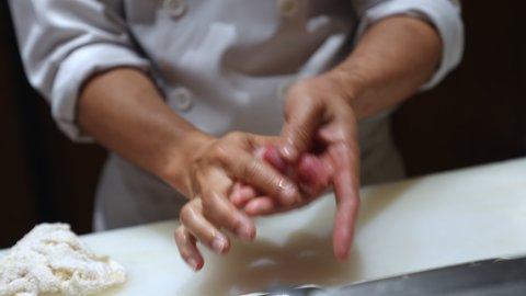Close up of Professional chef hand preparing tuna nigiri sushi on serving plate to customer. Handmade delicious healthy sushi menu fish with rice on open kitchen counter bar in japanese restaurant