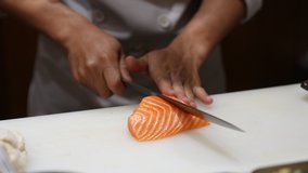 Close up of Professional male chef hand using fish fillet knife slice fresh orange salmon meat on cutting board in restaurant kitchen. Chef preparing healthy menu salmon sashimi or sushi to customer - Powered by Shutterstock - Get 15% off with code: PIKWIZARD15