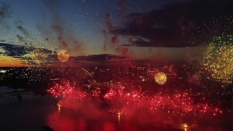 Aerial Fireworks in City Sky. New Year Eve Fly Drone Scene. City Night Lights. Flight Above Spark Firework Explode Festivities. Bright Festive Fireworks on Dark Urban Skyline Background. Holiday Fire