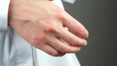 A woman scratches dry irritated skin with contact dermatitis. Allergic reaction and health. Skin care. Hands close-up.