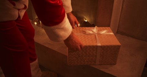 Close - up of Santas hand: brings gifts under the Christmas tree for children. Give gifts to children on Christmas night. Santa puts a gift under the Christmas tree