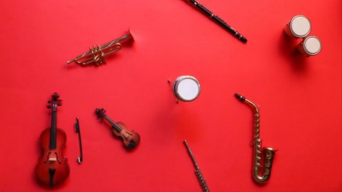 Moving instruments of jazz band or symphonic orchestra against red background, stop motion animation