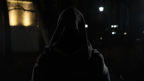 man in street at night in hood stands in front of camera. Scary ghost in night park with smoke around. Horror of the city with black hood. - Powered by Shutterstock - Get 15% off with code: PIKWIZARD15