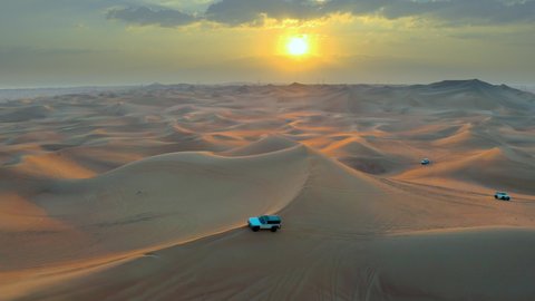 Desert Safari off-road with sunset view. car vehicle rides on desert dune barkhan or sand-dune. Aerial drone view.