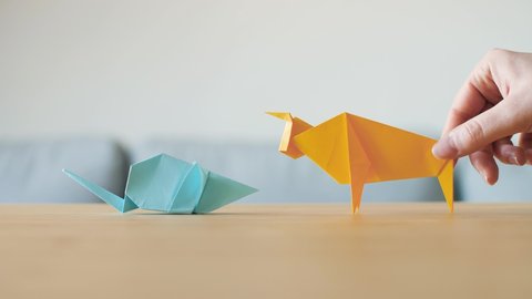 An Origami Rat and Ox meet on table. Zodiac animals change for Chinese new year. The cow is the Chinese zodiac sign for 2021 and mouse for 2020. Animals made by hand by traditional paper folding. 4K.