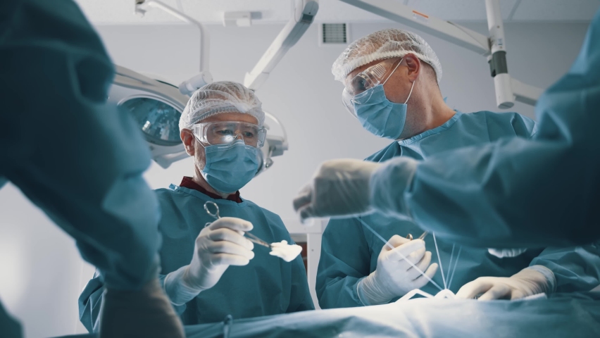 Multi-age group of caucasian doctors performing professional heart surgery operation in operating medical room. Modern hospital. Teamwork. Royalty-Free Stock Footage #1063026457