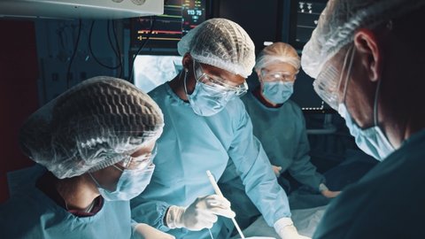 Team of professional multi-race doctors operating surgery in hospital room. Patient undergoing serious heart transplant surgery. Healthcare. Lockdown.