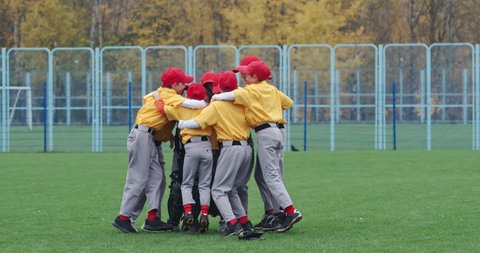 Baseball at school, a team of boys baseball players in yellow uniforms get hugs and rejoices in victory, successful game, positive emotions, 4k Slow Motion.