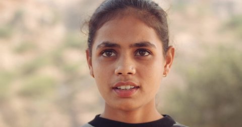 Slow-motion CU of an Indian teen girl outdoors as she is looking at camera and talking 