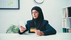 Muslim businesswoman using smartphone and credit card