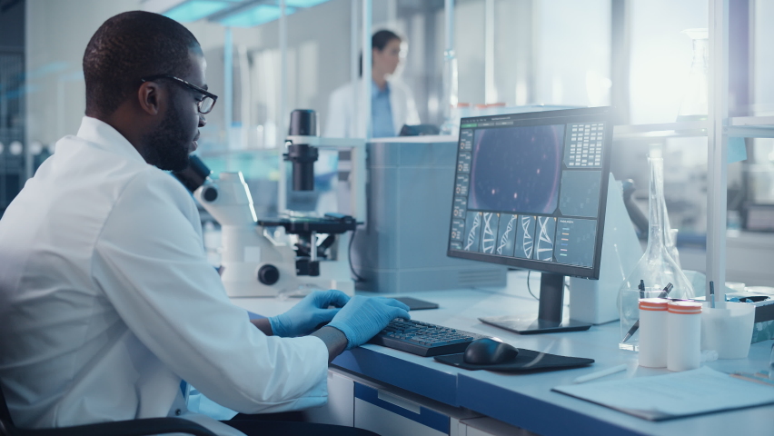 Modern Medical Research Laboratory: Portrait of Male Scientist working on Computer Showing DNA concept. Scientific Lab and Medicine Development Facility with Advanced Equipment, Biotechnology Royalty-Free Stock Footage #1063037629
