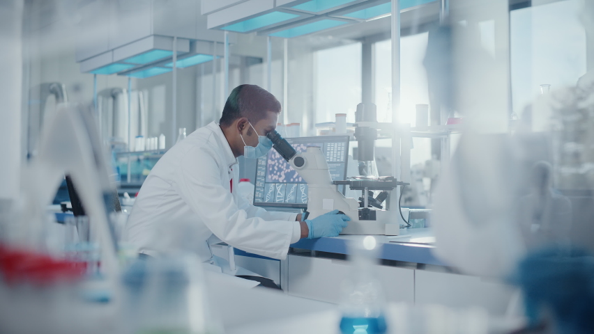 Medical Research Laboratory: Focus Shifting from Male Scientist Looking Under Micrsocope to Female Scientist Working with Micro Pipette. Advanced Scientific Lab Biotechnology, Medicine Development Royalty-Free Stock Footage #1063037653