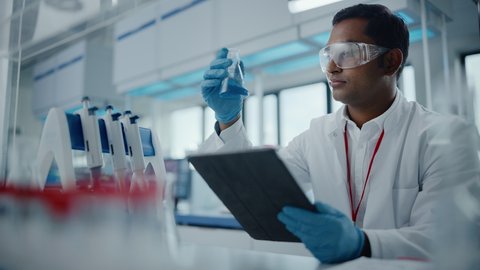 Medical Research Laboratory: Portrait of a Handsome Male Scientist Using Digital Tablet Computer to Analyse Data. Advanced Scientific Lab for Medicine, Biotechnology, Microbiology Development