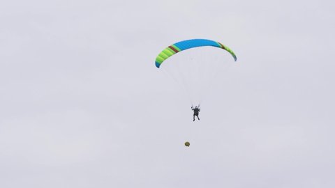 Bottom view of man with parachute in sky. Action. Person flies in sky on paraglider in cloudy weather. Extreme sports and skydiving