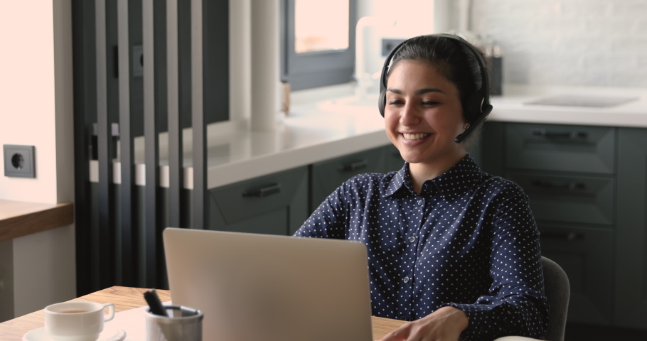 Happy young indian woman in headphones with mic holding online job interview with hr manager from home, sharing working experience, making self-presentation or discussing project with colleagues. Royalty-Free Stock Footage #1063054063
