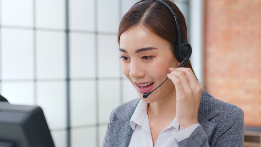 Closeup Asian woman call center, customer service, telesales in formal suit wearing headset or headphone talking with customer in modern office | Shutterstock HD Video #1063059109