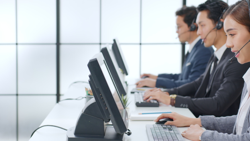 Asian call center team, customer service, telesales in formal suit wearing headset or headphone talking with customer in modern office Royalty-Free Stock Footage #1063059127