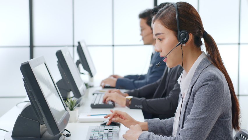 Asian call center team, customer service, telesales in formal suit wearing headset or headphone talking with customer in modern office | Shutterstock HD Video #1063059127