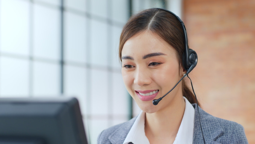 Closeup Asian woman call center, customer service, telesales in formal suit wearing headset or headphone talking with customer in modern office | Shutterstock HD Video #1063059172
