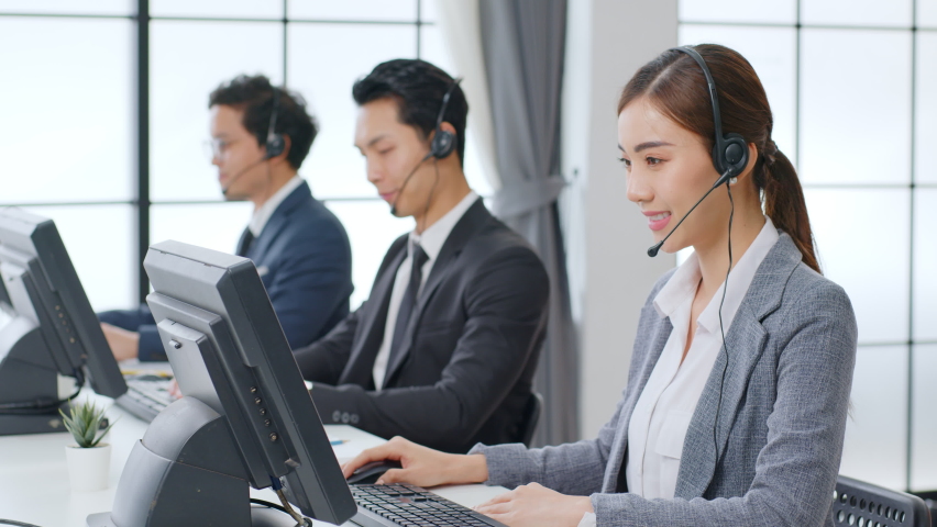 Asian call center team, customer service, telesales in formal suit wearing headset or headphone talking with customer in modern office Royalty-Free Stock Footage #1063059181