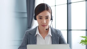 Young Asian businesswoman, call center, customer service with headset or headphone talking on video call conference or virtual meeting in office