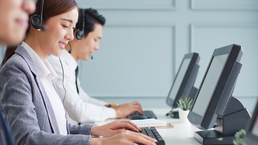 Asian call center team, customer service, telesales in formal suit wearing headset or headphone talking with customer in modern office Royalty-Free Stock Footage #1063059355