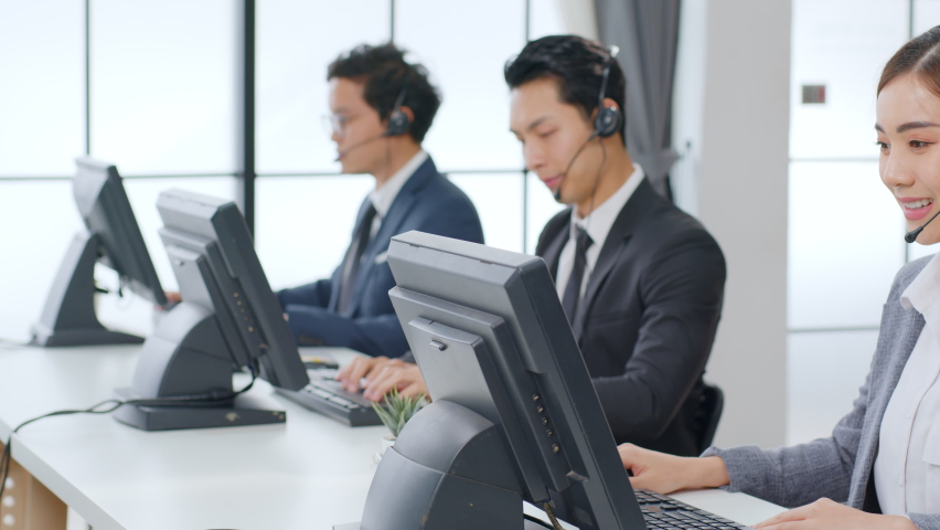 Asian call center team, customer service, telesales in formal suit wearing headset or headphone talking with customer in modern office Royalty-Free Stock Footage #1063059388