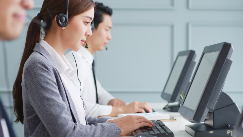 Asian call center team, customer service, telesales in formal suit wearing headset or headphone talking with customer in modern office Royalty-Free Stock Footage #1063059391