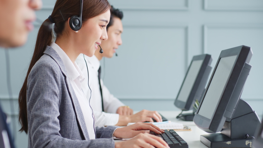 Asian call center team, customer service, telesales in formal suit wearing headset or headphone talking with customer in modern office | Shutterstock HD Video #1063059391