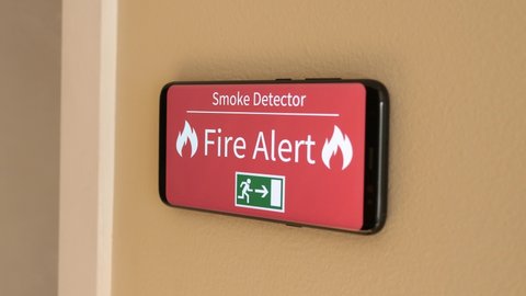 Smoke detector on a wall warning about the smoke present in the air.