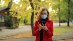 Social distancing, online video chat, woman in surgical mask call his friend at the autumn park
