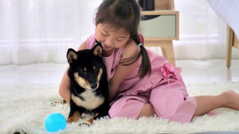 Asian little girl having fun playing with her dog at home.