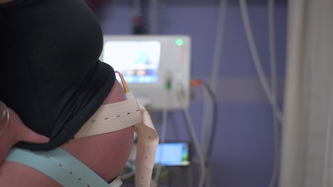 A Cardiotocograph machine monitors a heavily pregnant woman's unborn baby's heartbeat in the hospital while in active labour.