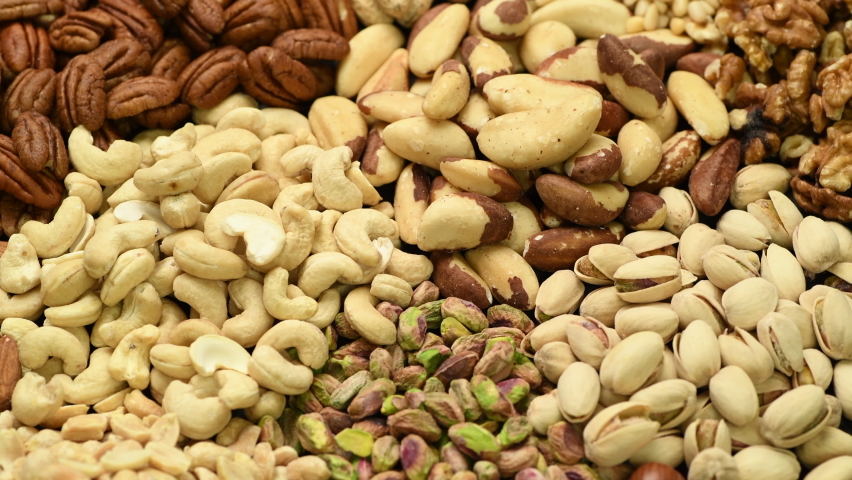 Assortment of various nuts such as cashew nuts, brazil nuts, peanuts, almonds, pecan and other, rotating Royalty-Free Stock Footage #1063077835