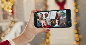 Close up of smartphone screen with multiple online video call between multi-ethnic friends on Xmas Eve. African American couple videochatting. 2021 New Year. Hand holding cellphone with video chat