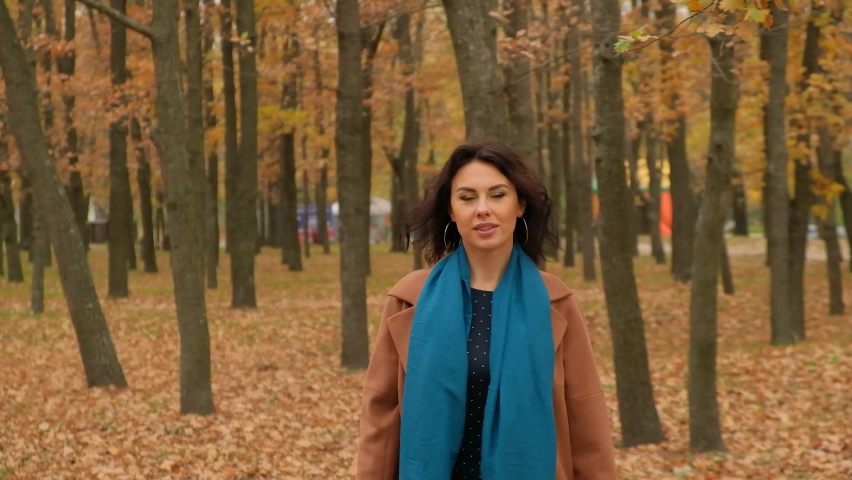 Young beautiful girl walks in the park among yellow trees in autumn.