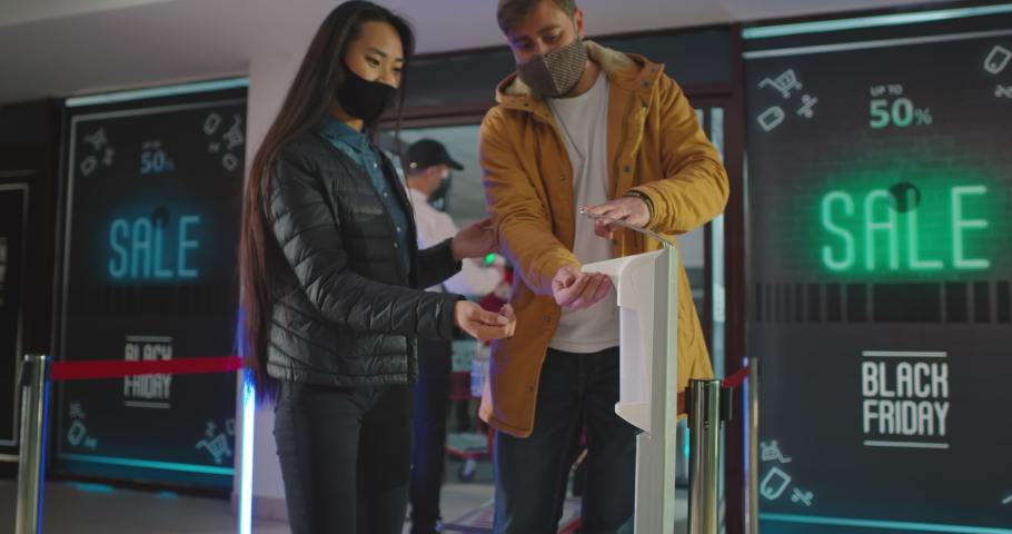 Pan right view of diverse people taking sanitizer while walking past guard with contactless thermometer | Shutterstock HD Video #1063078372