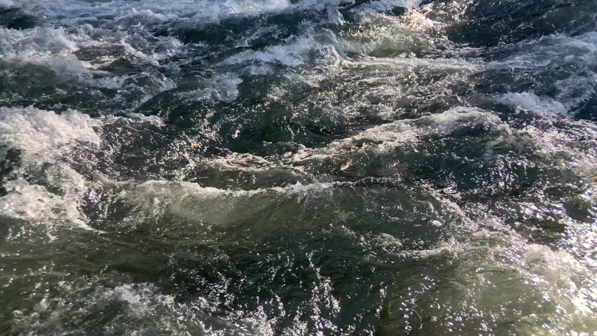 Close-up of whitewater rapids from a glacial mountain river, showing intense surface movement. Static shot.