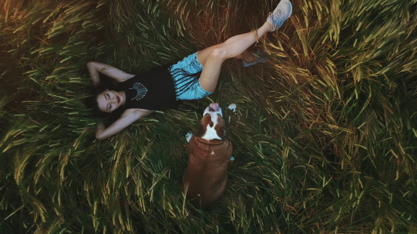 Beauty Girl with summer cowboy hat Outdoors. Happy Smiling Young Woman falling down on the yellow grass. Beautiful young woman lying on the field. Enjoying Nature. Slow motion video footage.
