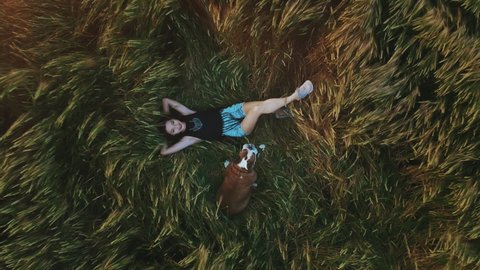 Beauty Girl with summer cowboy hat Outdoors. Happy Smiling Young Woman falling down on the yellow grass. Beautiful young woman lying on the field. Enjoying Nature. Slow motion video footage.