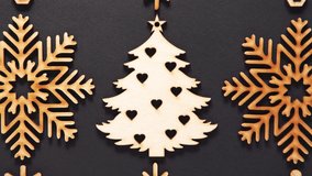 Handmade wooden decorations for Christmas and New Year celebration filmed in flat lay 4K on black background.Beautiful fir tree and snowflakes made from natural wood material for home decor in winter