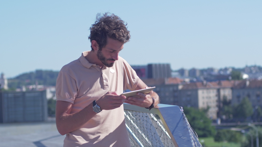 Young good looking man with stylish clothes using a smartphone in a terrace. Trendy modern hipster enjoying carefree lifestyle outdoors. 