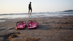 Boy walking towards flip flops on sandy beach shore video background in 60 FPS 