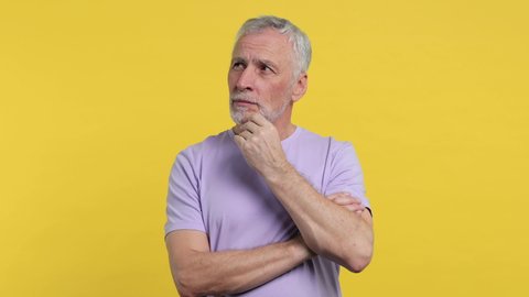Puzzled pensive elderly gray-haired mustache bearded man in casual violet t-shirt isolated on bright yellow color background studio. People lifestyle concept. Looking aside put hand prop up on chin